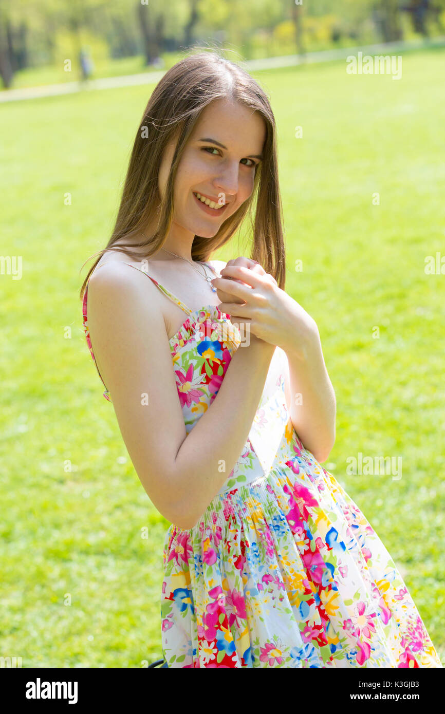 Portrait of young Beautiful woman with long hair wearing flower dress in green spring park Banque D'Images