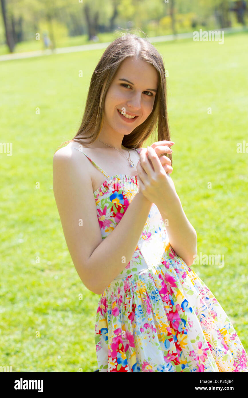 Portrait of young Beautiful woman with long hair wearing flower dress in green spring park Banque D'Images