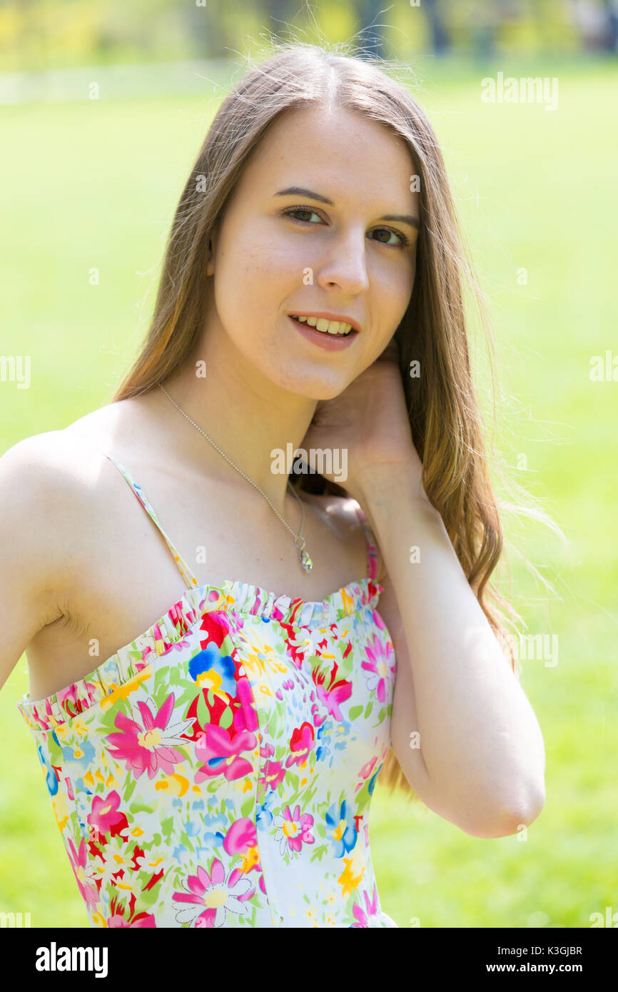 Portrait of young Beautiful woman with long hair wearing flower dress in green spring park Banque D'Images