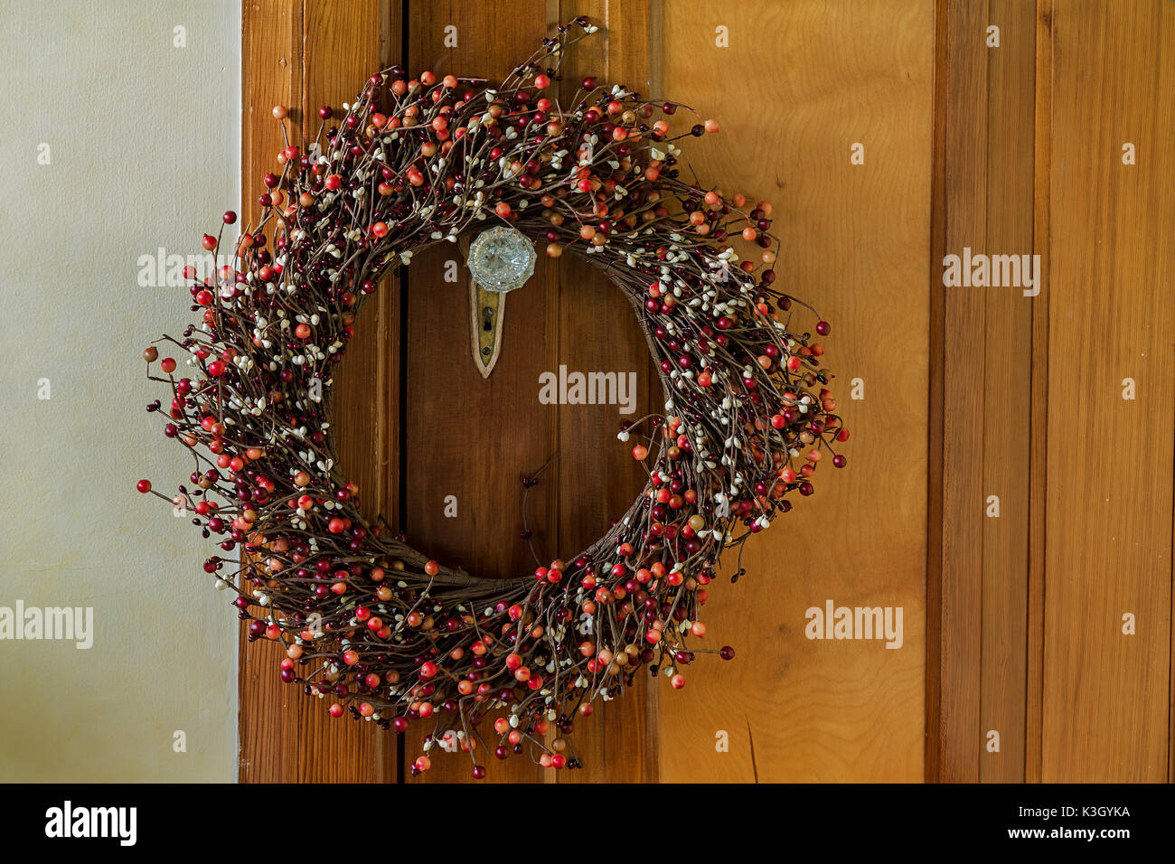 Noël wreathhanging Berry sur la poignée d'une porte ancienne. Banque D'Images