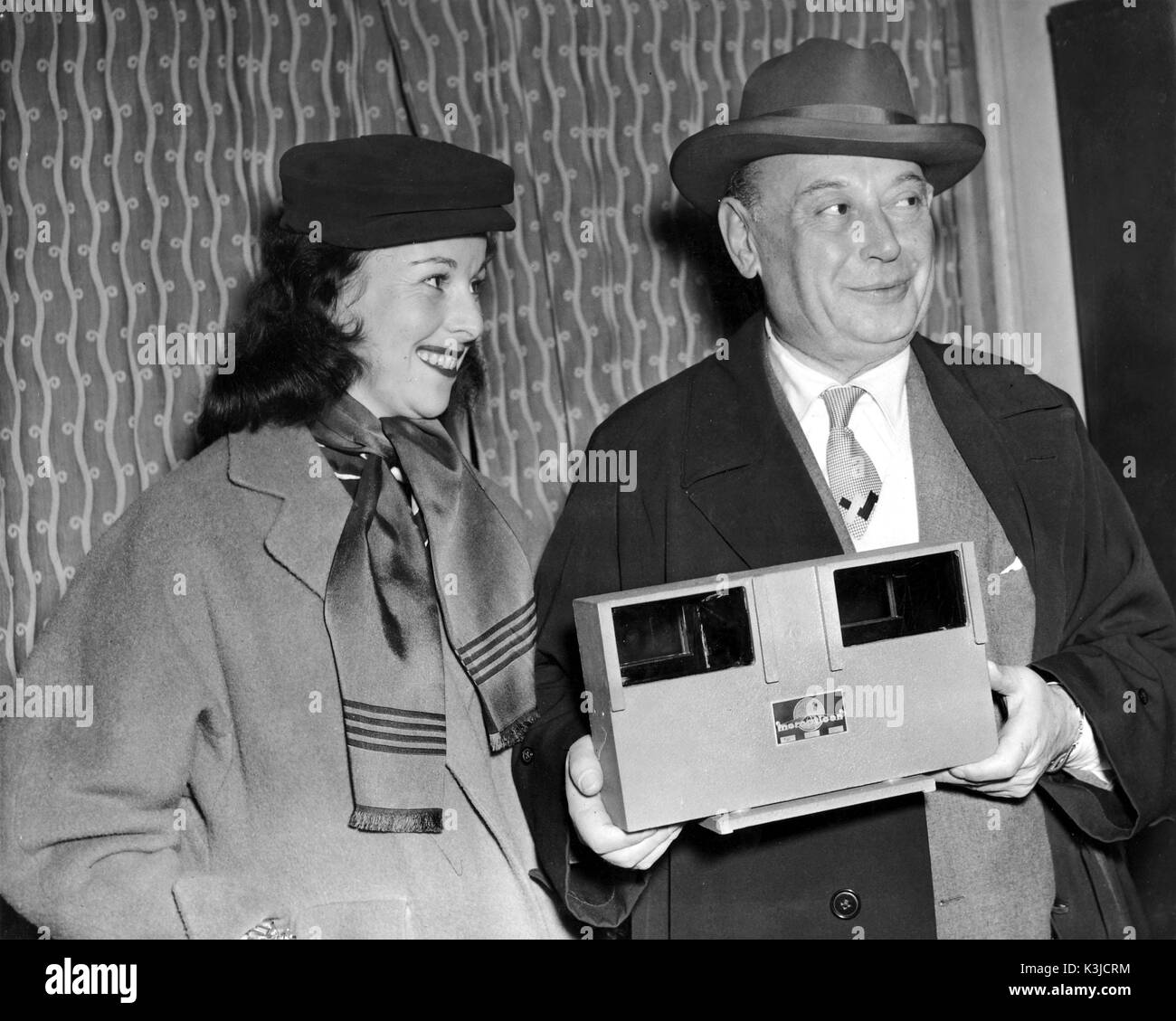BORIS MORROS, le producteur d'Hollywood, après 4 ans et demi à Vienne, arrive à l'aéroport de Londres avec son 'magic box'. Cette invention est un système 3D qui utilise seulement un film. Il est accompagné de sa secrétaire Marion Sklarz Banque D'Images
