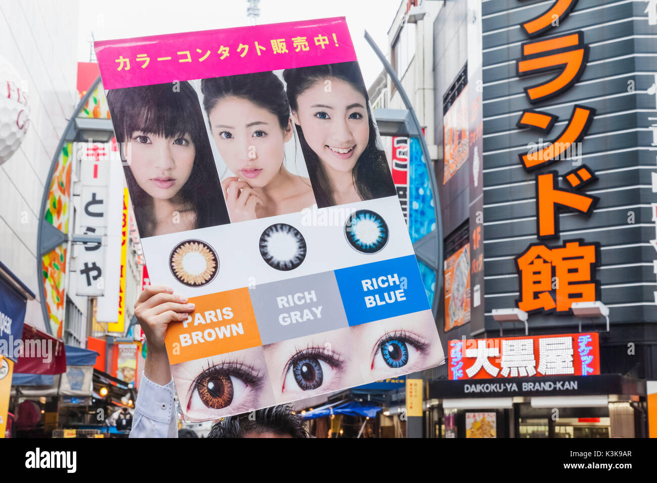 Japon, Tokyo, Ueno, Hoshu Ameyoko, rue Commerçante, Man Holding panneau publicitaire pour les lentilles de contact Banque D'Images