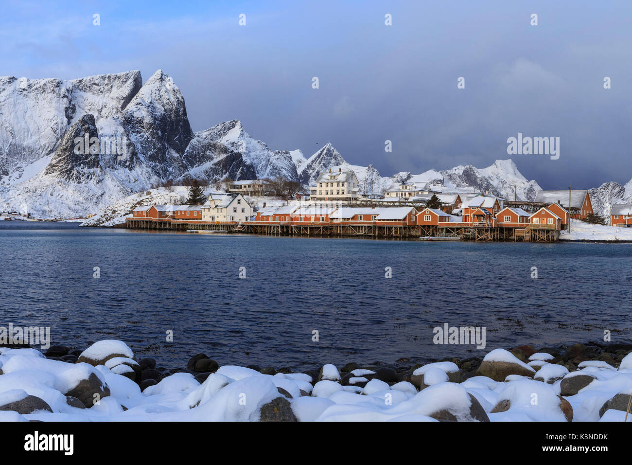 Maisons sur pilotis contre les sommets de montagne et ciel couvert, Moskenes, îles Lofoten, Norvège Banque D'Images
