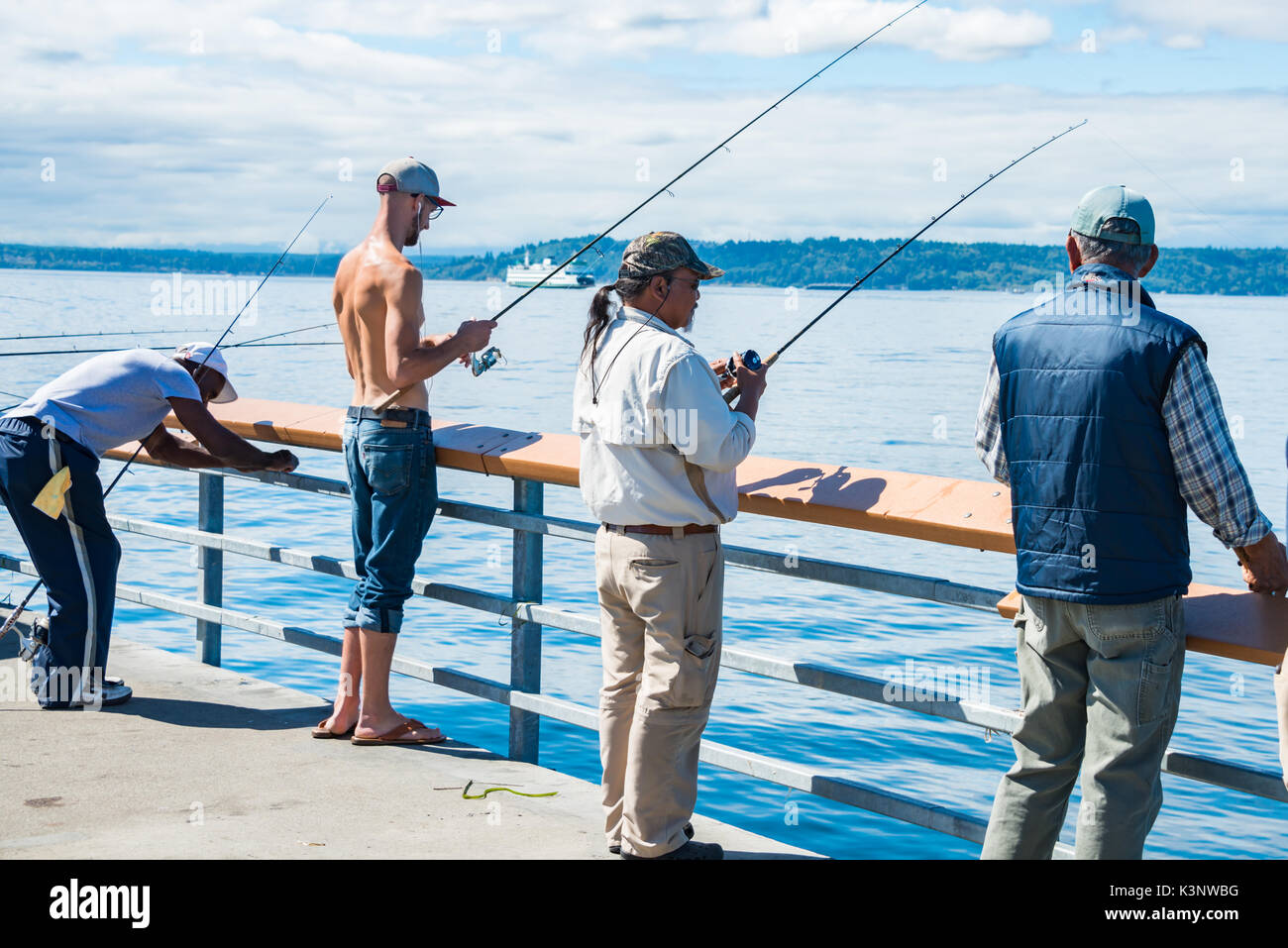 Divers groupes d'hommes La pêche au large de l'embarcadère de ferry avec en arrière-plan, Edmonds, Washington Banque D'Images