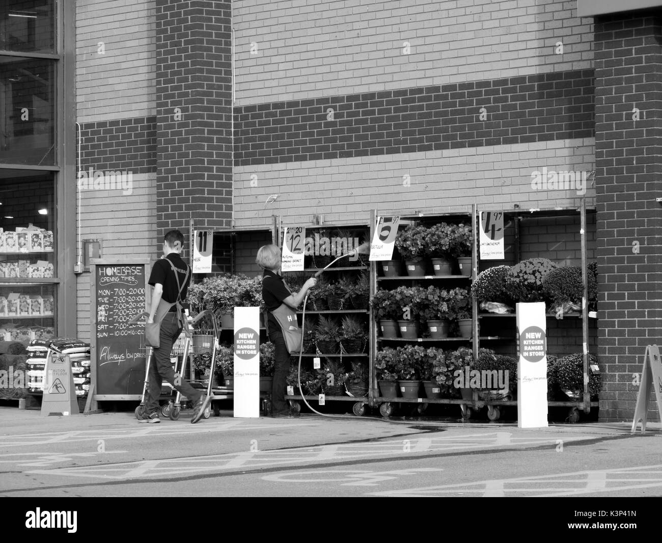 Homebase (centre de rénovations et de garden centre, les employés de l'entreprise l'arrosage des plantes Banque D'Images