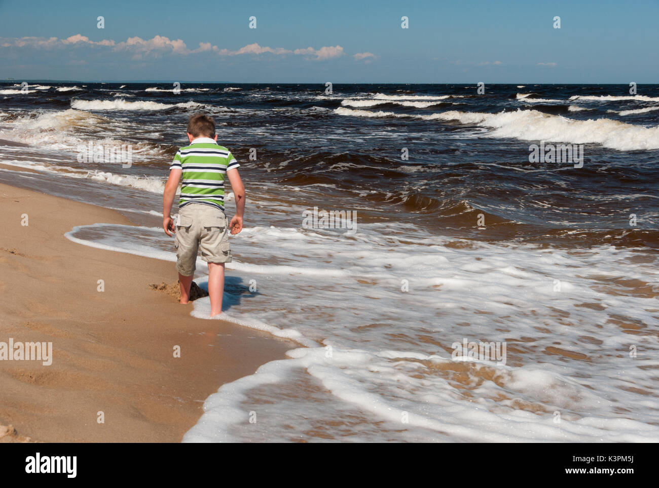 Un garçon Marche à une plage en Suède. Banque D'Images