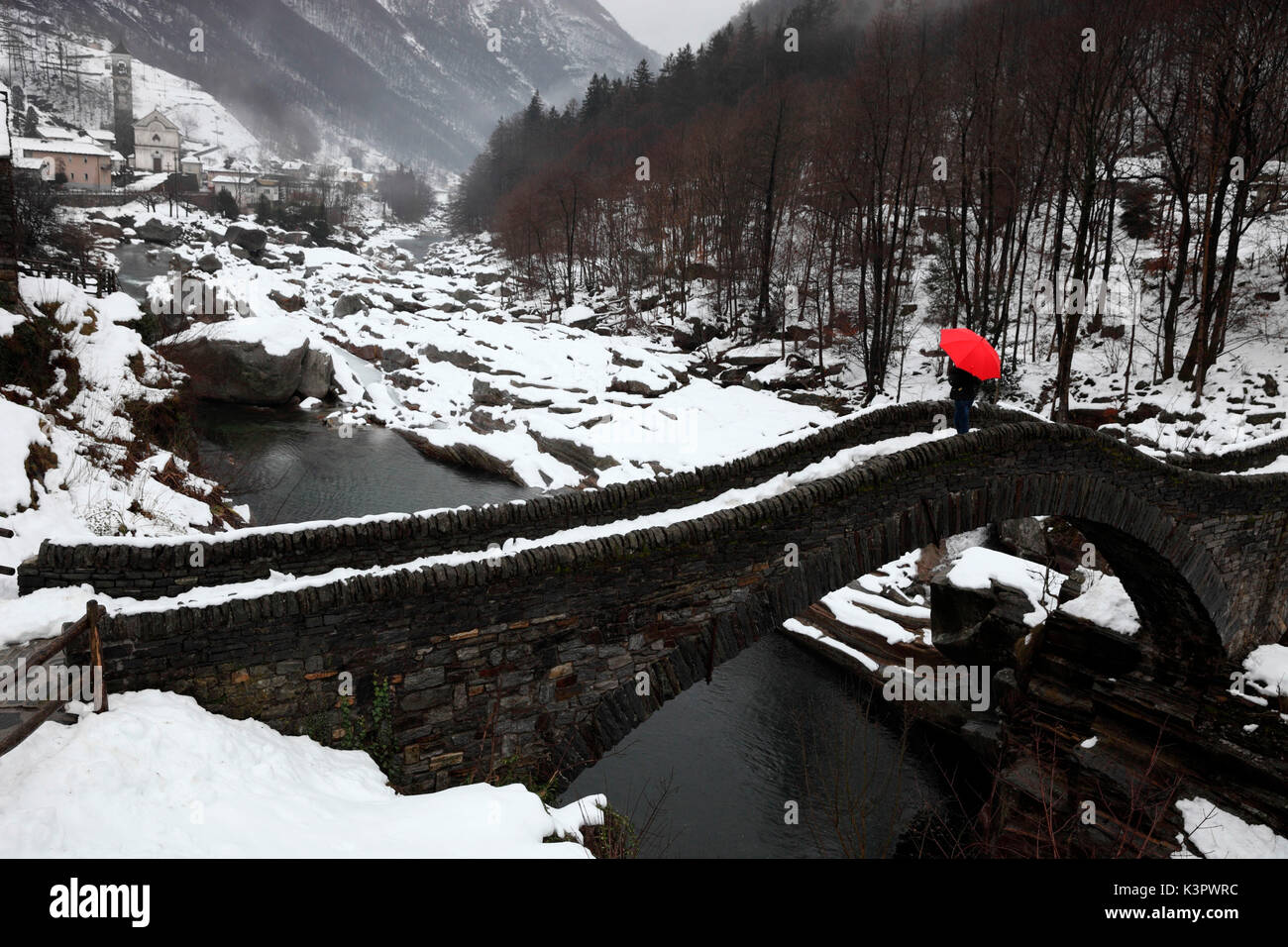 Fille avec un parapluie rouge sur Ponte dei Salti de Lavertezzo en hiver, Val Verzasca, Tessin, Suisse Banque D'Images