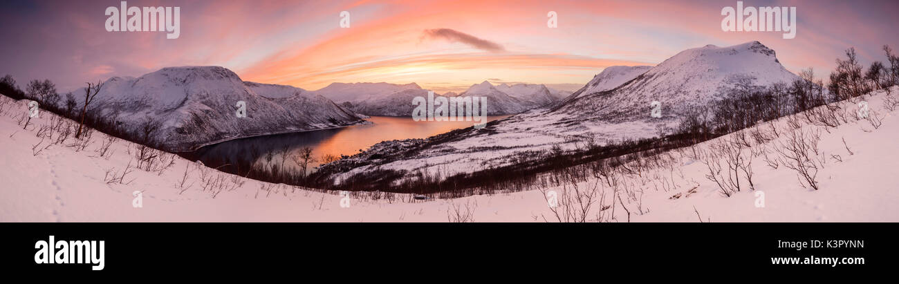 Panorama de la mer congelés entouré par la neige encadré par les nuages orange au coucher du soleil Gryllefjorden Senja Troms County Norvège Europe Banque D'Images