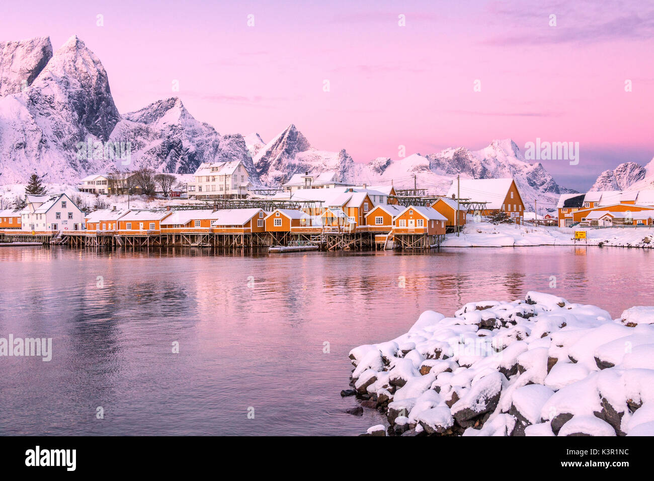 Les couleurs de l'aube les cadres de maisons de pêcheurs entouré de sommets enneigés Sakrisøy Reine Nordland îles Lofoten Norvège Europe Banque D'Images