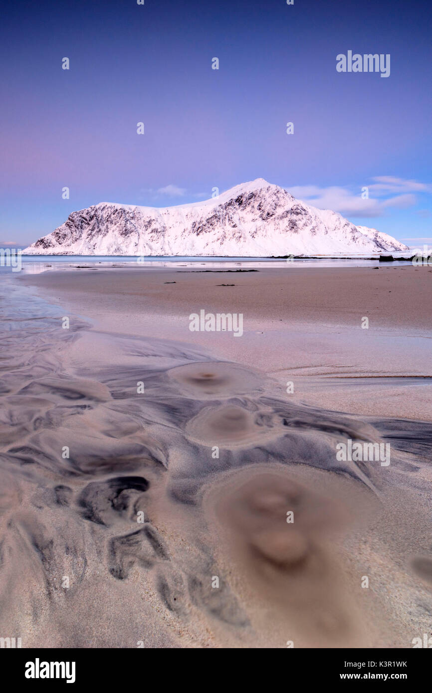 Ciel rose et des sommets enneigés encadrent la plage au coucher du soleil Skagsanden surréaliste Flakstad Nordland County Iles Lofoten Norvège Europe Banque D'Images