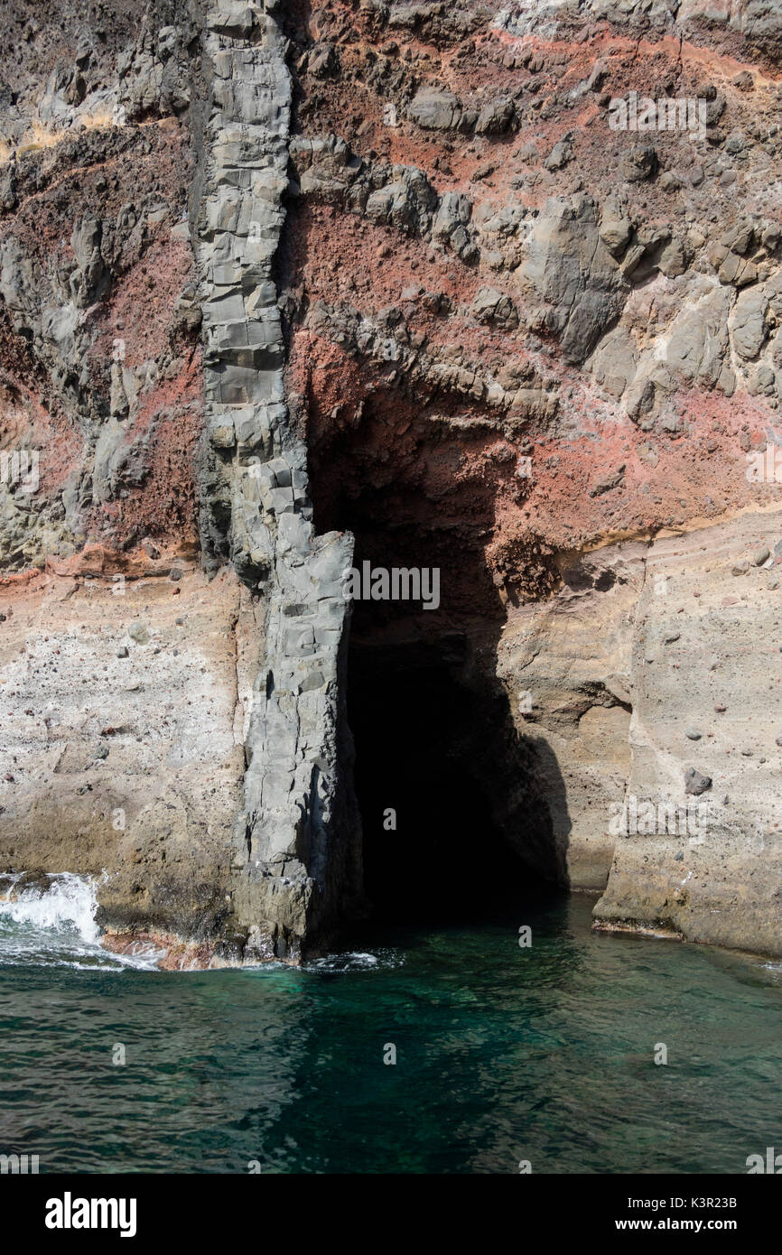 La mer turquoise autour d'une grotte surgi entre les roches volcaniques typiques de l'île de Santorini Cyclades Grèce Europe Banque D'Images