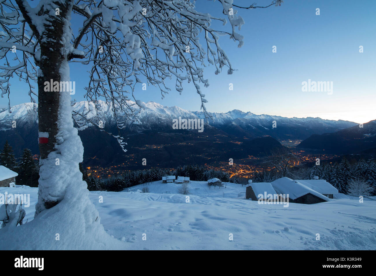 Lumières de crépuscule illuminent la vallée et les huttes couvertes de neige Tagliate Di Sopra Gerola Valley Valteline Lombardie Italie Europe Banque D'Images