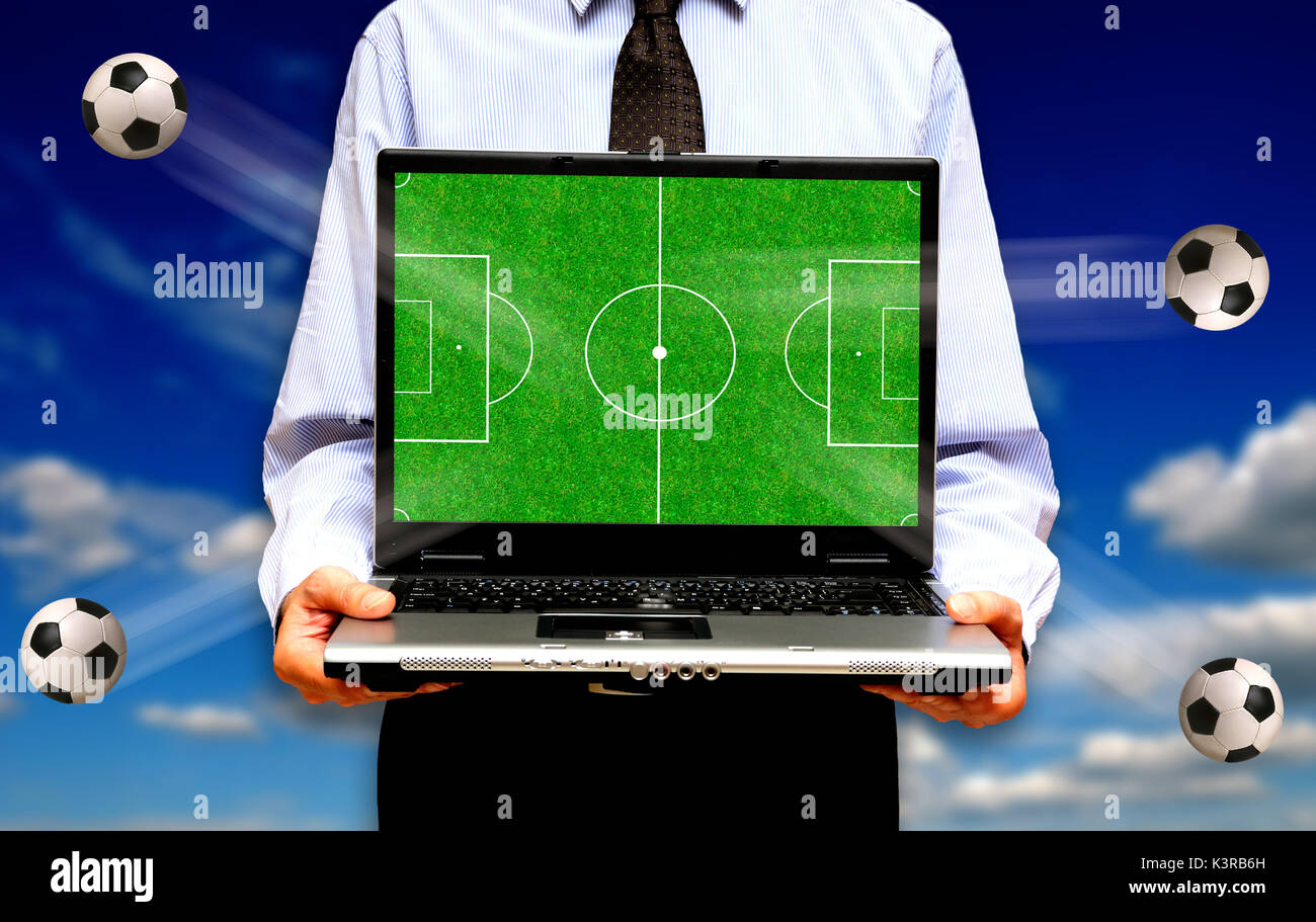 Homme montrant un terrain de football sur un écran de l'ordinateur portable,  le soccer en ligne ou le streaming football en ligne Photo Stock - Alamy