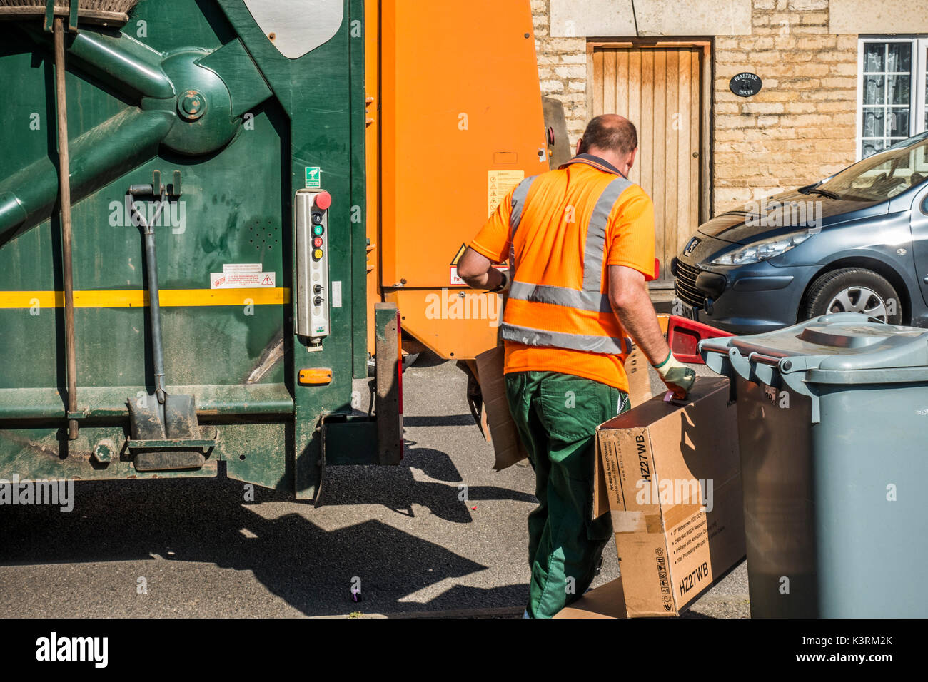 Un conseil ouvrier en tenant le carton déchets à la refuser camion sur une journée ensoleillée. Langtoft, près de Peterborough. Lincolnshire, Angleterre, Royaume-Uni. Banque D'Images