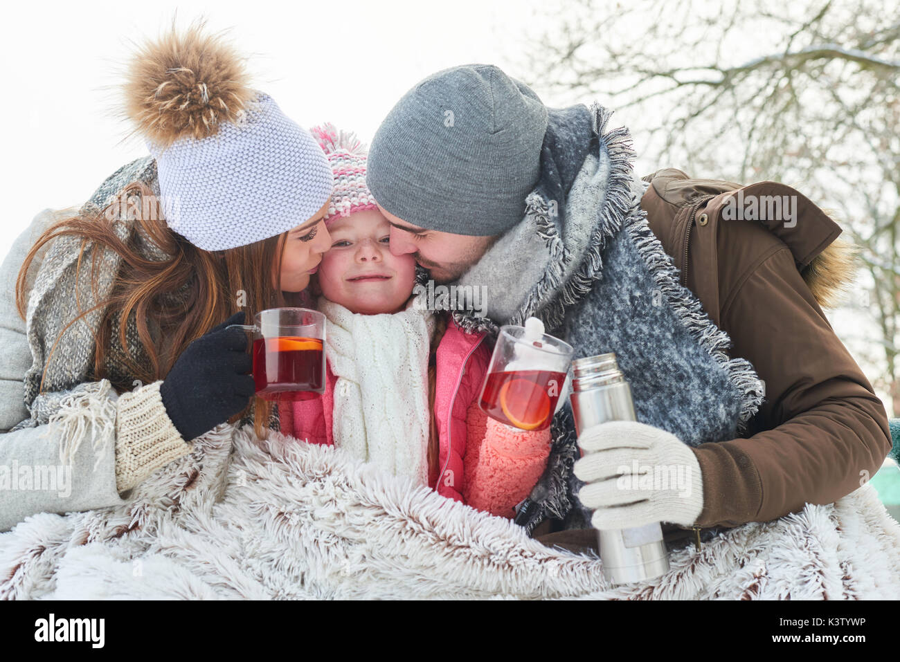 Famille avec enfant de boire du thé et de câlins en hiver Banque D'Images