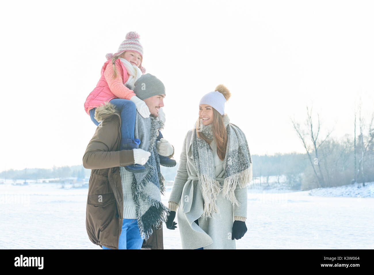 Les parents d'enfant en tant que famille en hiver en prenant une marche avec un piggyback ride Banque D'Images