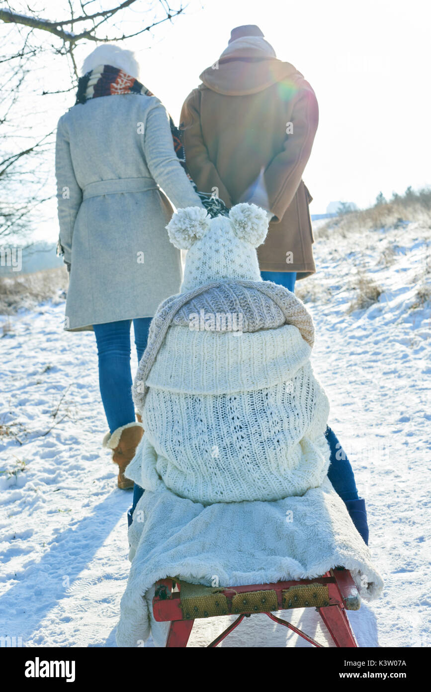 Tirez sur les parents de l'enfant luge whilte de prendre une marche dans la neige en hiver Banque D'Images