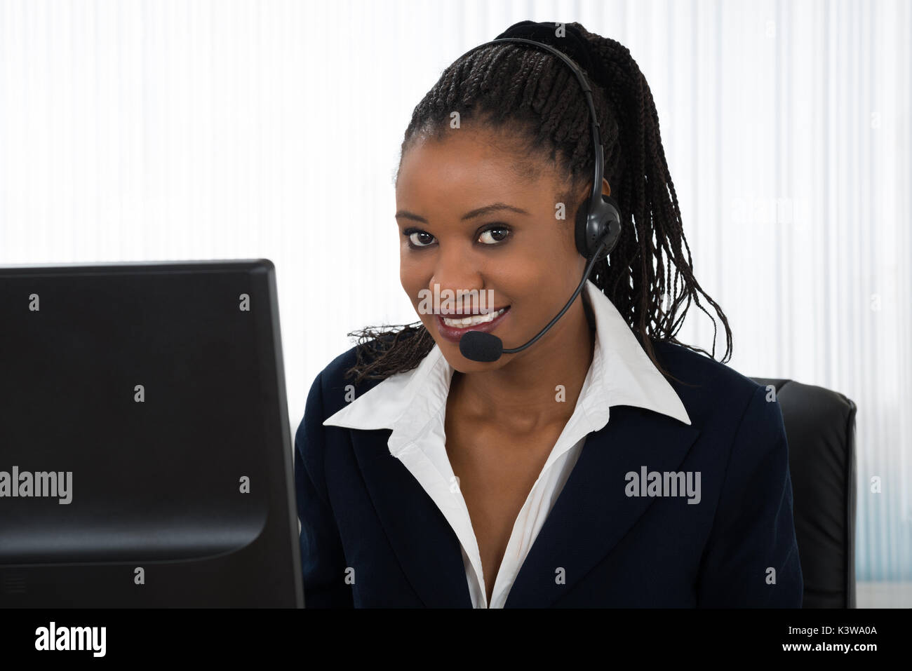 Portrait Of A Young Smiling Businesswoman Talking On Headset Banque D'Images