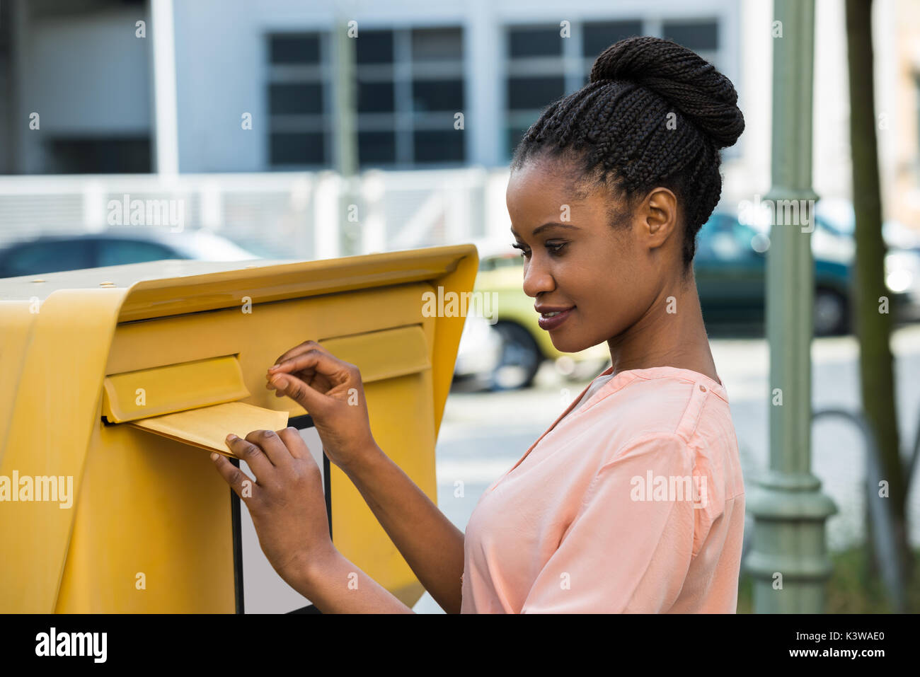 Jeune femme africaine l'insertion lettre dans la boîte aux lettres Banque D'Images