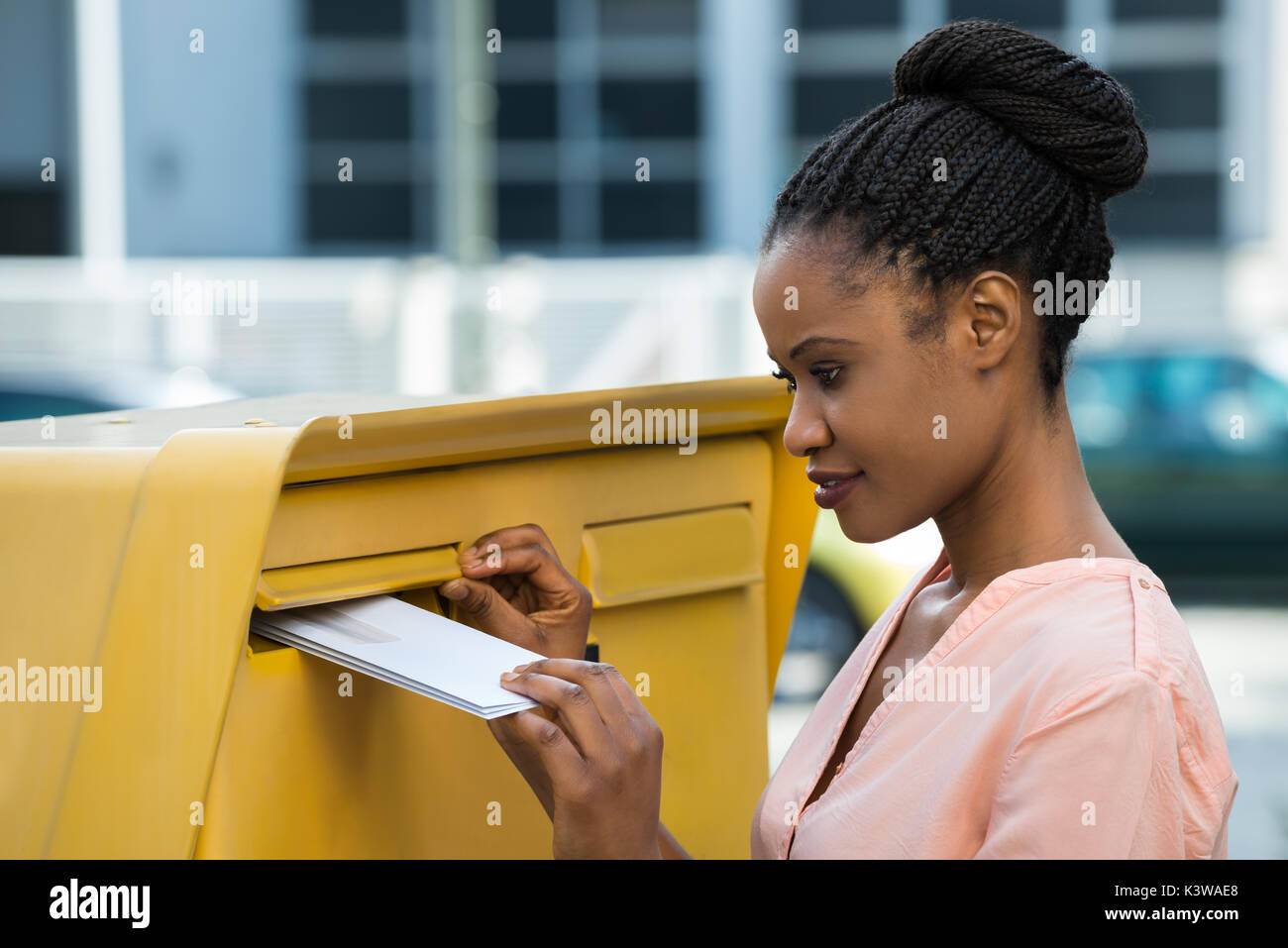 Jeune femme africaine l'insertion lettre dans la boîte aux lettres Banque D'Images