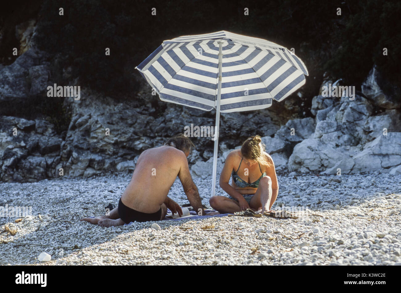 Une paire est sous un parasol sur la plage, Crete, Grèce. Banque D'Images