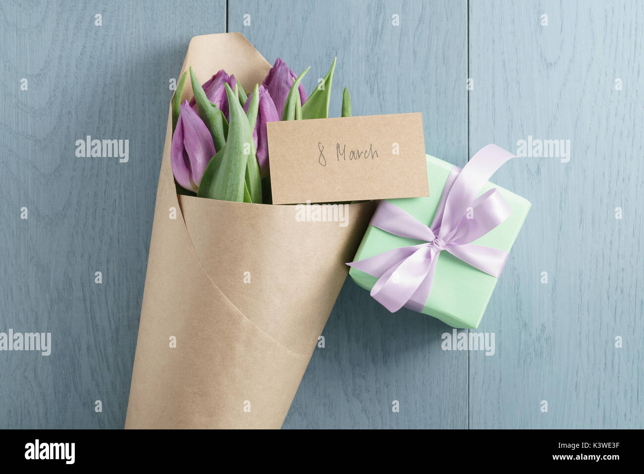 Vue de dessus du don avec tulipes pourpres dans du papier craft sur fond de bois bleu avec 8 carte de mars Banque D'Images