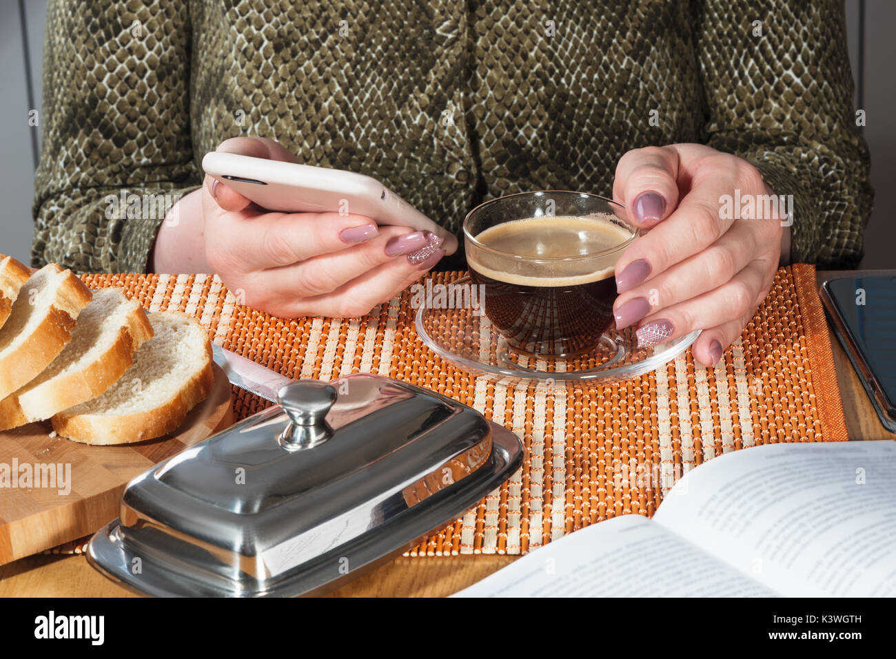 Tasse en verre avec du café noir et le téléphone dans les mains avec manucure Banque D'Images