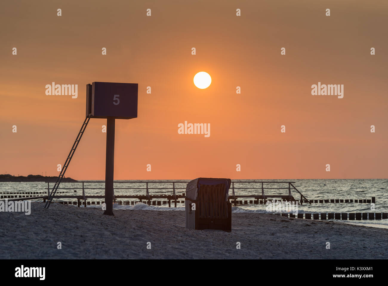Strandkorb am menschenleeren Ausguck und mit vor der Sonne untergehenden, Heiligenhafen, Schleswig-Holstein, Allemagne Banque D'Images