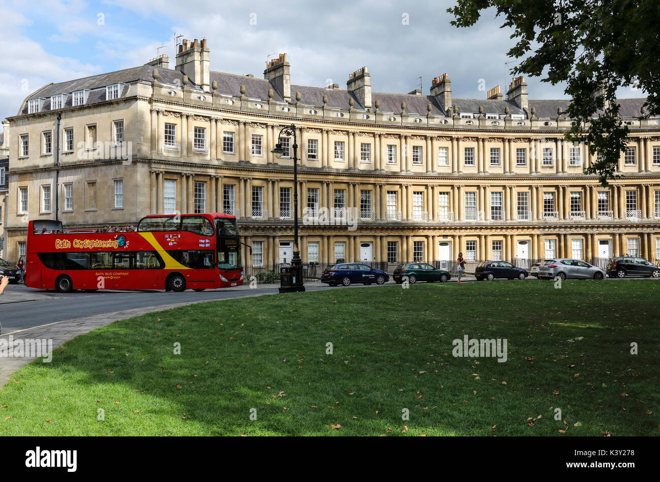 Un bus touristique rouge arrivant au Circus, Bath, Somerset, Angleterre, Royaume-Uni. Un site classé au patrimoine mondial de l'UNESCO. Banque D'Images