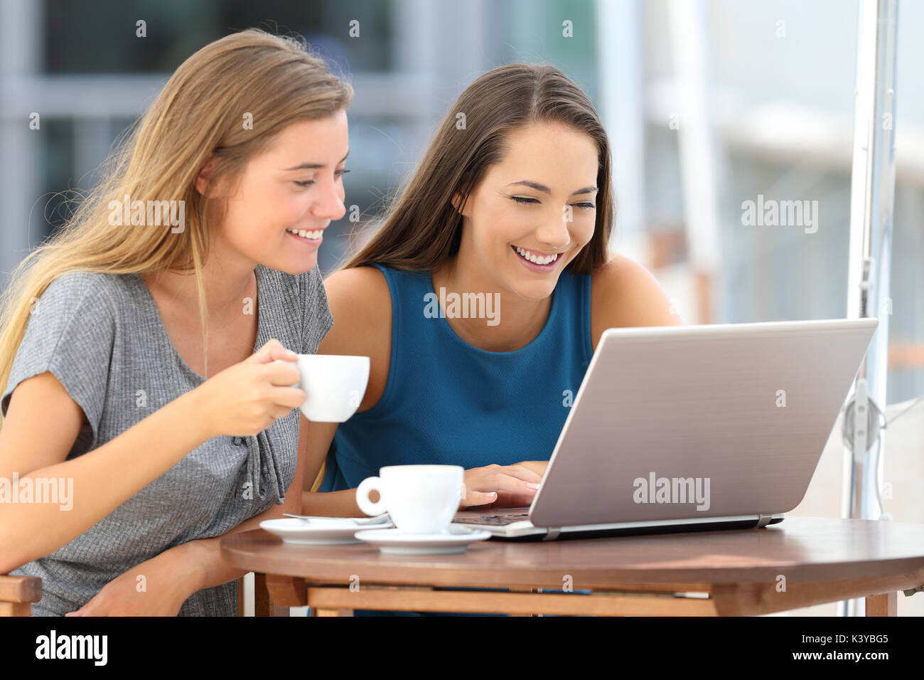 Deux amis drôle de regarder du contenu multimédia dans un ordinateur portable assis dans un bar Banque D'Images
