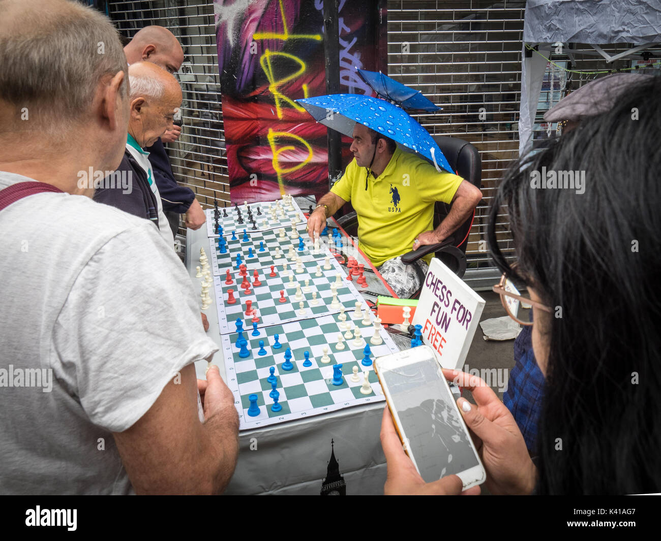 Brick Lane Chess - un joueur joue 4 matchs simultanés avec les touristes et les passants à Londres, Brick Lane Market Dimanche Banque D'Images