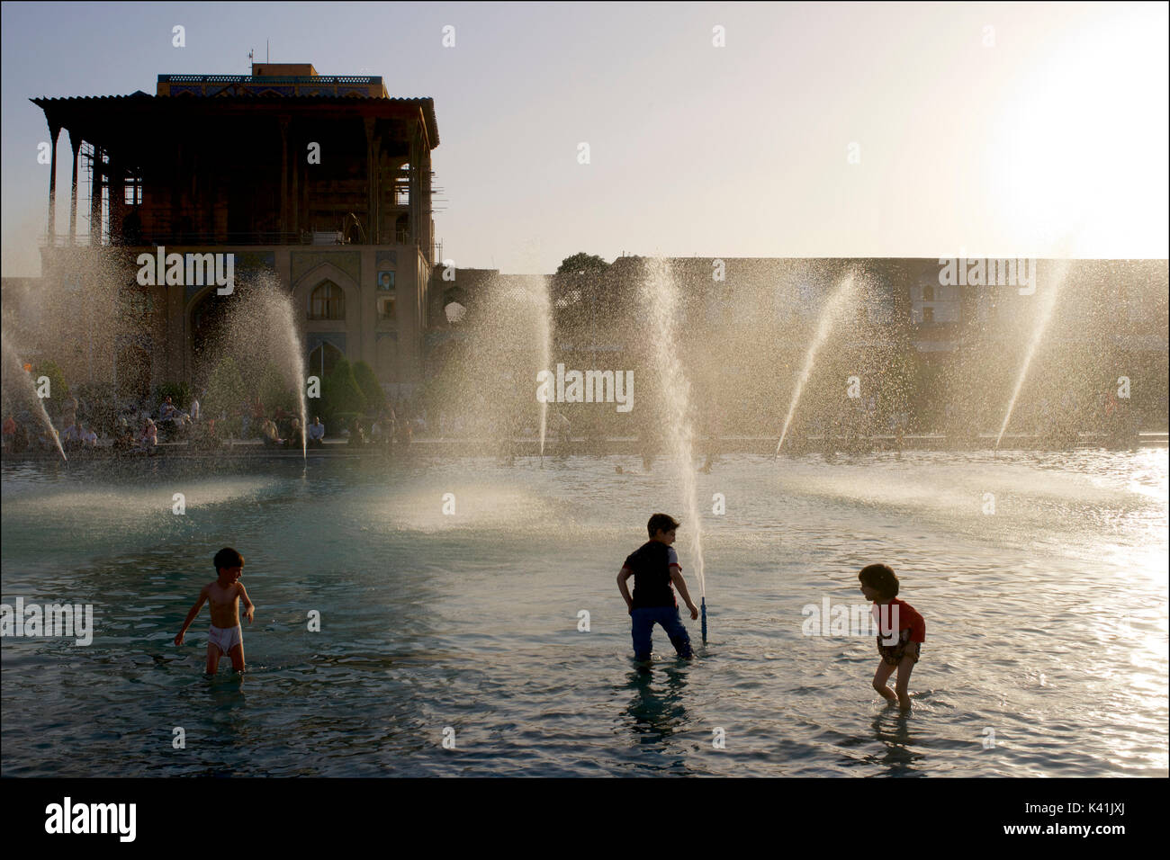 Les enfants jouant dans les fontaines en face de Palais Ali Qapu, place Imam. Naqsh-e Jahan Isfahan, Iran ville Banque D'Images