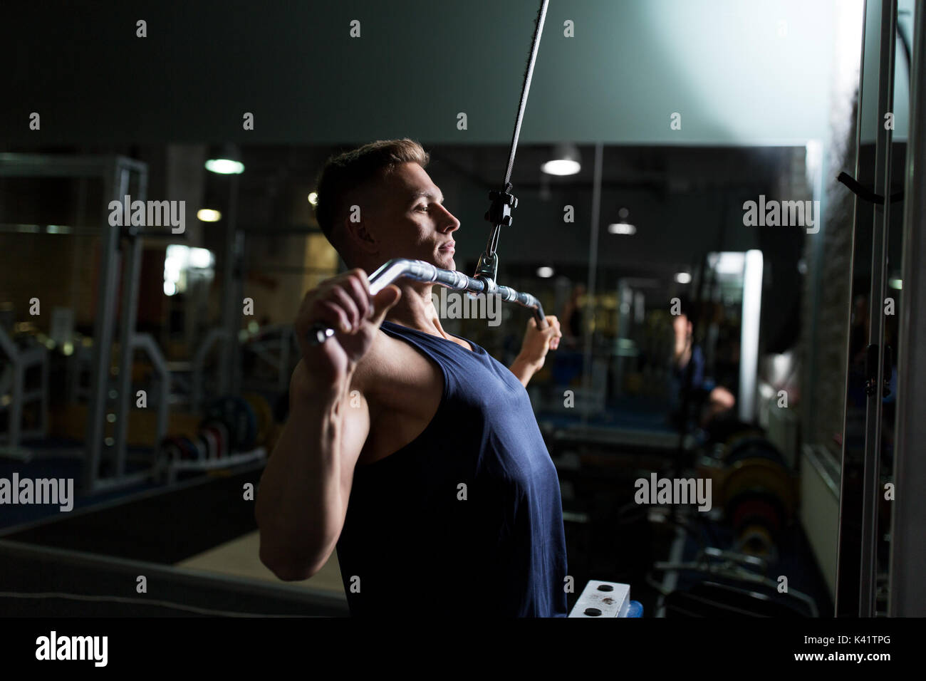 Man flexing muscles sur le câble de la machine en salle de sport Banque D'Images