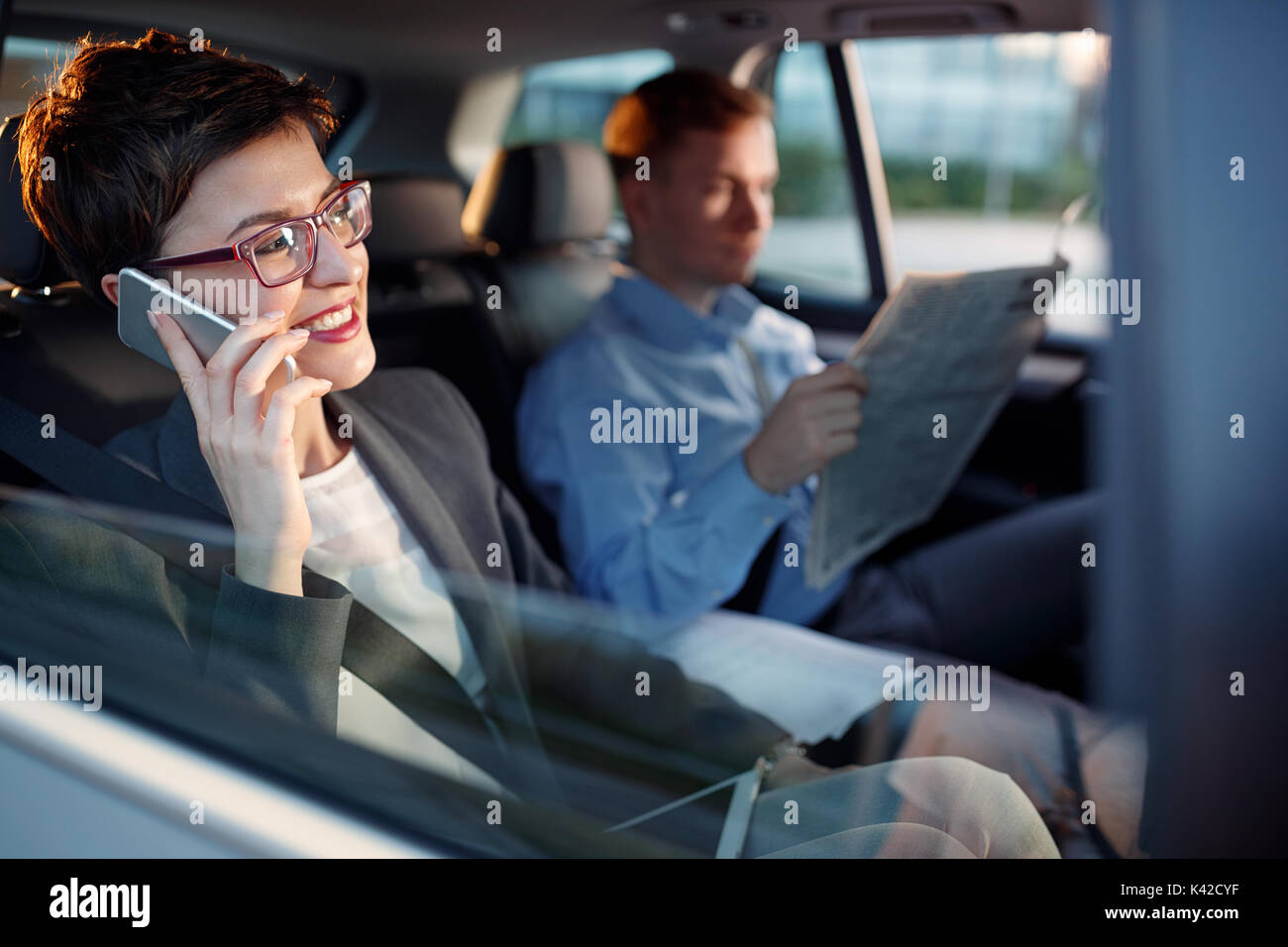 Souriante jeune femme d'affaires smartphone utiliser dans la voiture Banque D'Images