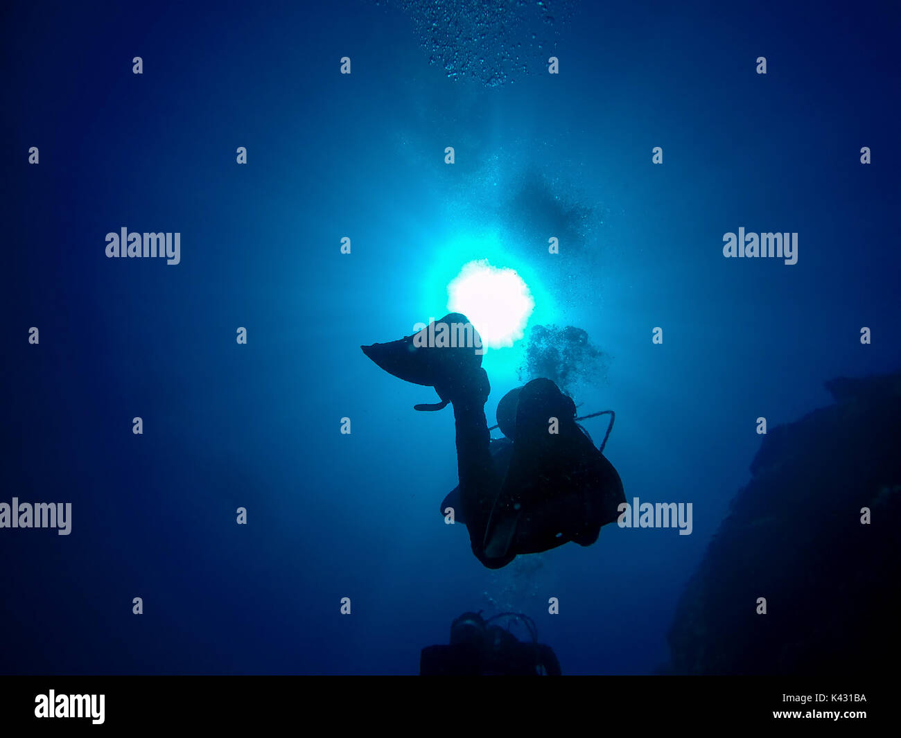 Groupe de plongeurs sous-ordre croissant. Un écran rétroéclairé scuba diver silhouette. Vue de la plongée sous marine et de bulles sous l'eau dans le bleu profond de la mer contre la Banque D'Images