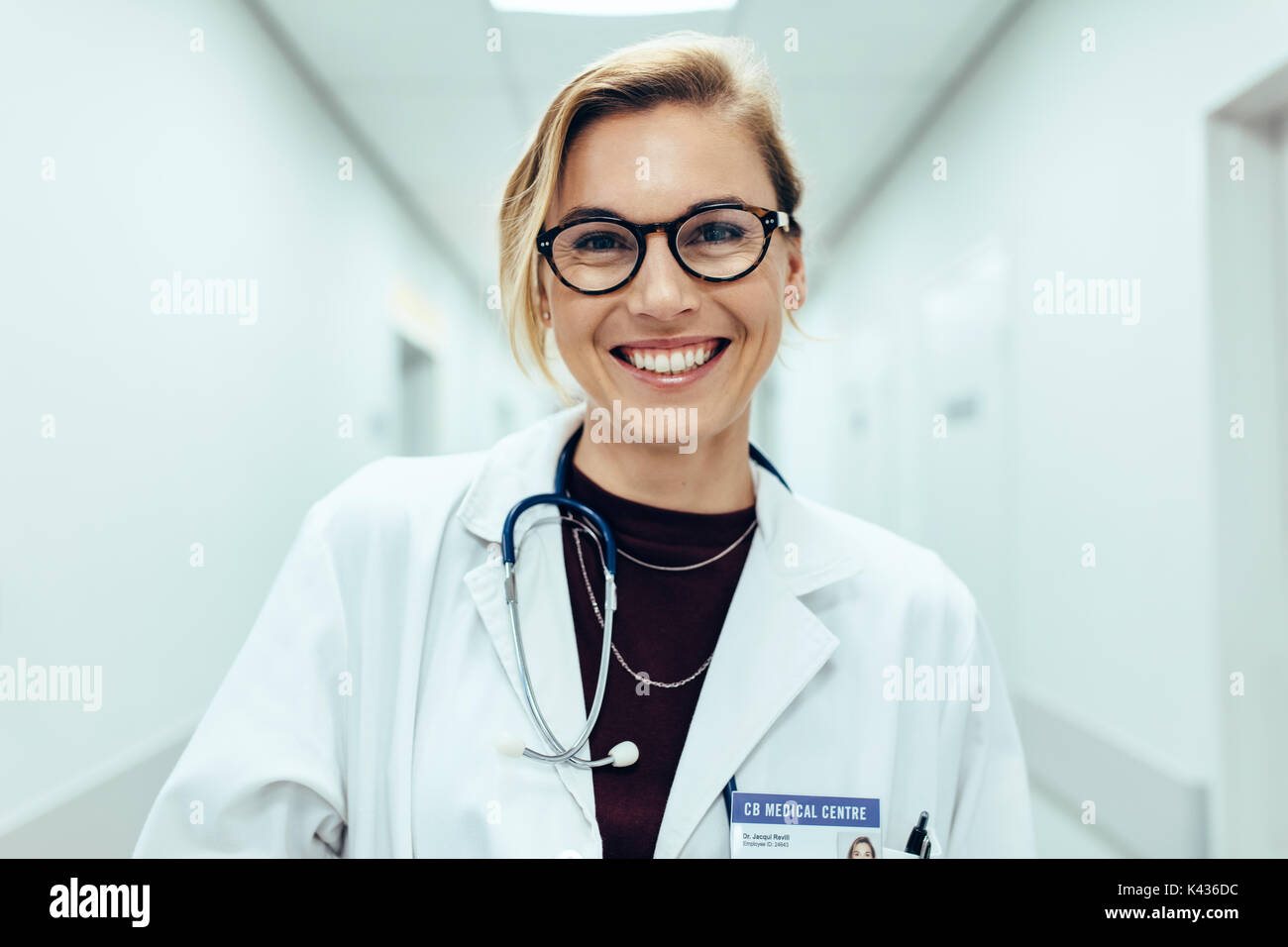 Portrait of happy young female doctor standing in hospital corridor. Caucasian woman travaillant en centre de santé. Banque D'Images
