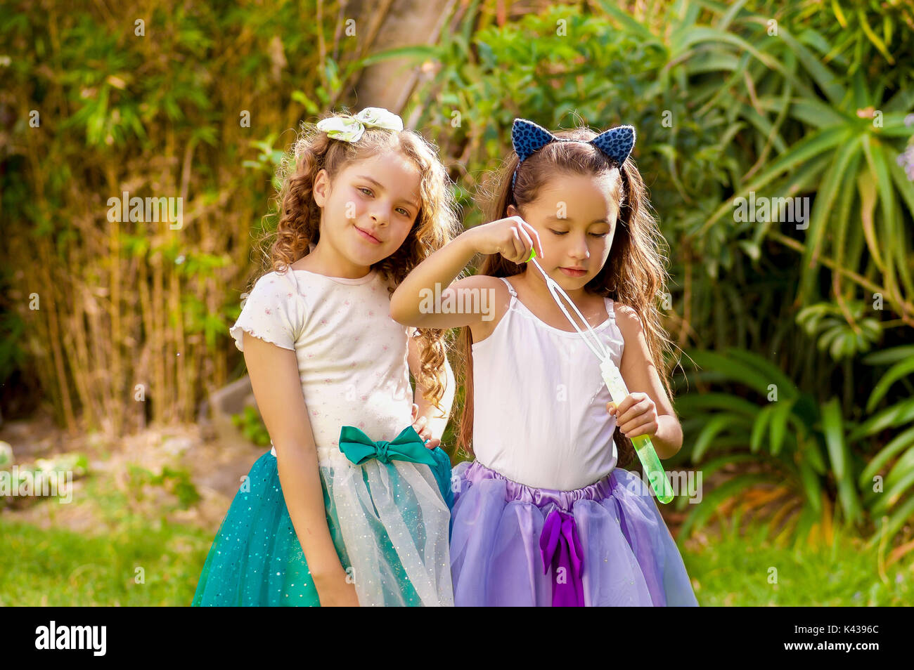 Heureux deux magnifiques petites filles jouant avec des bulles de savon sur  une nature d'été, une fille porte une oreille bleu accessoires tigre sur sa  tête et les deux filles portant une