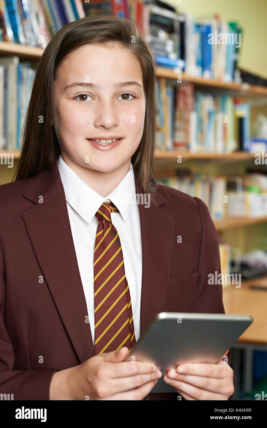 Portrait of Girl Wearing School Uniform Using Digital Tablet In Library Banque D'Images