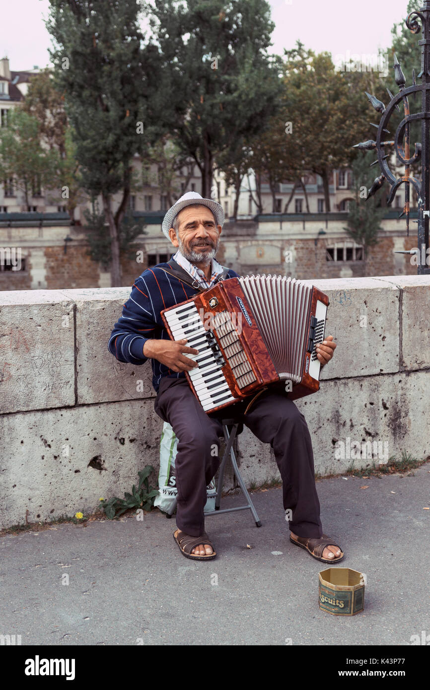Musicien de rue de la rue avec un accordéon sur les rives de la Seine, à côté de la cathédrale Notre-Dame. Paris, France. Banque D'Images