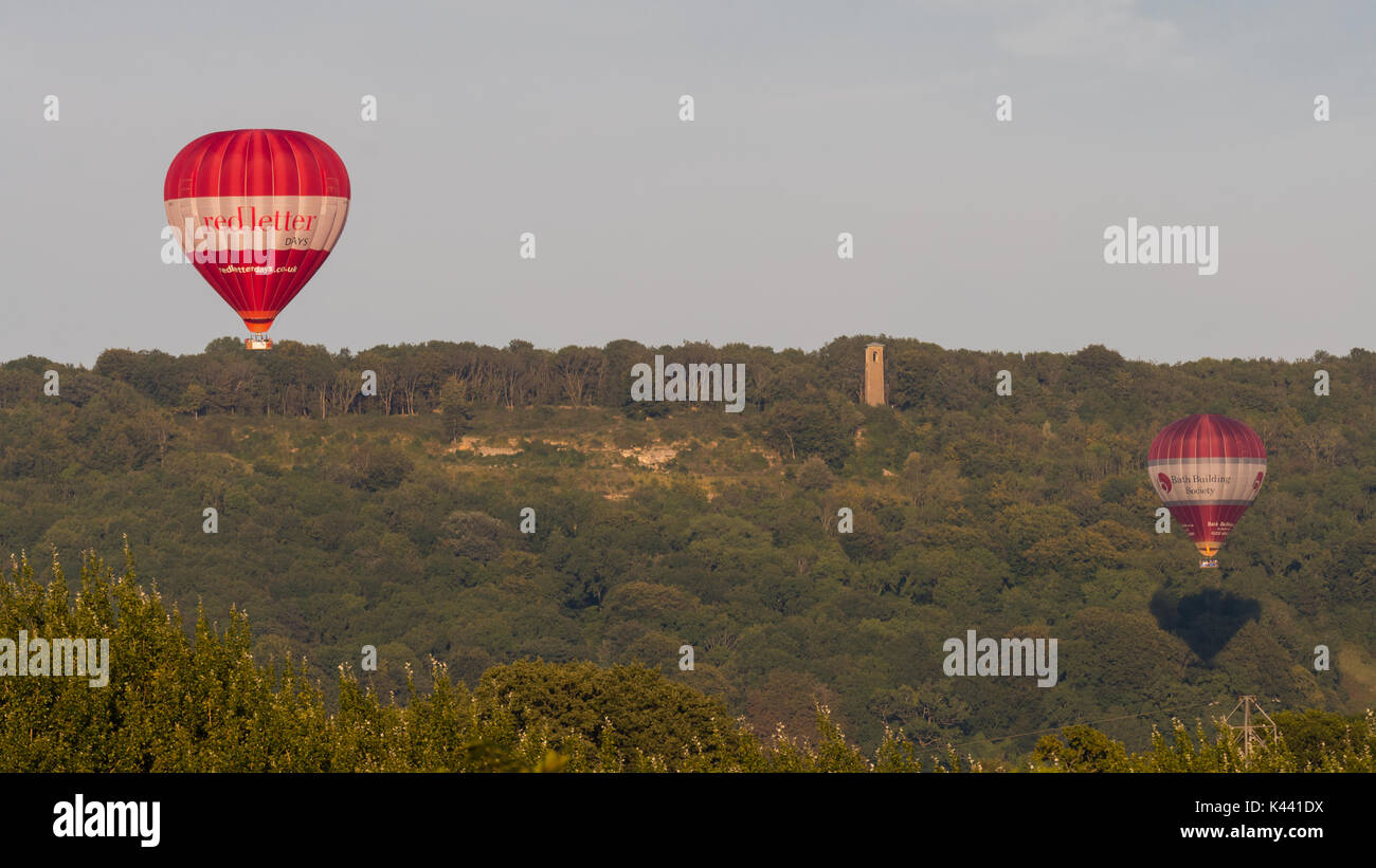 BATH, Royaume-Uni - 28 AUG 2017 Liveried montgolfières en face de Brown's Folly. Le rouge et le blanc les ballons servant au transport de personnes au-dessus de campagne dans le Somerset Banque D'Images