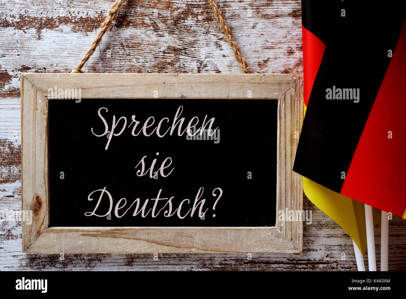 Un tableau en bois avec la question Sprechen Sie Deutsch ? Parlez-vous  allemand ? Rédigé en allemand, et quelques drapeaux de l'Allemagne contre  un cadre rustique Photo Stock - Alamy