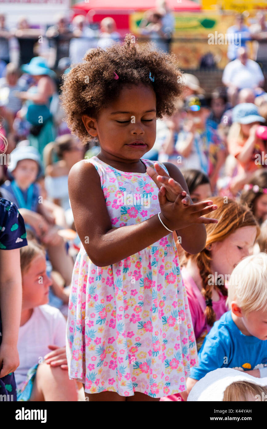 L'enfant noir, 5-6 ans, debout parmi foule des enfants assis, les yeux fermés tout en applaudissant et expression du visage très intense de concentration. Banque D'Images