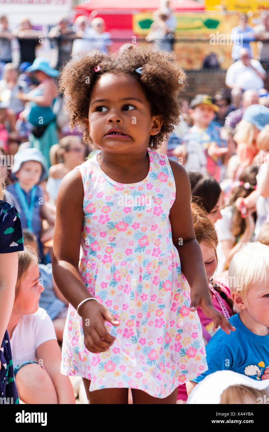 L'enfant noir, 5-6 ans, au milieu de la foule, les yeux des enfants assis à côté de l'cornerned très intense avec l'expression du visage. Banque D'Images