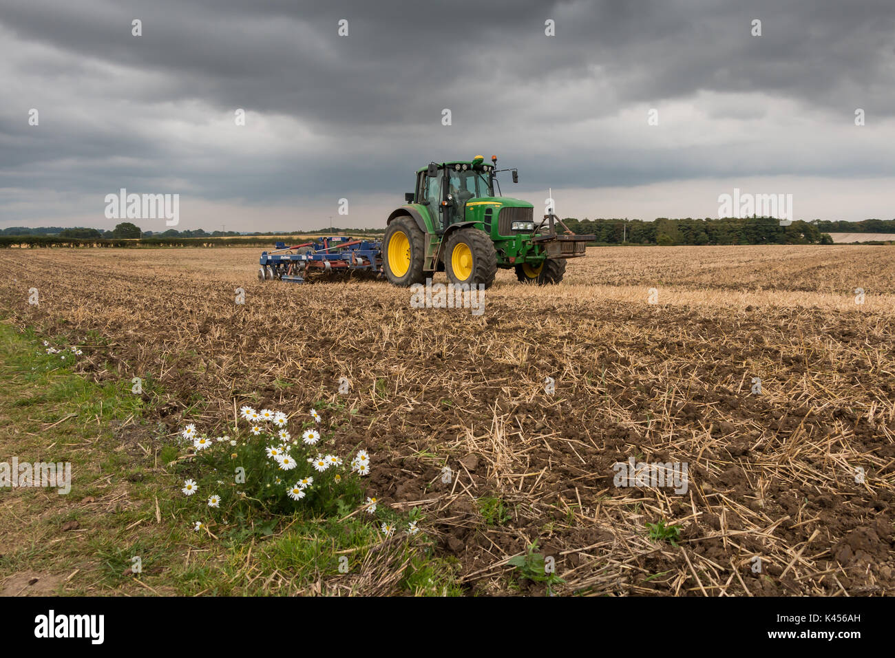 L'agriculture britannique - 4 mètre pliant Philip Watkins presse traîné et John Deere 7530 Premium au travail de cultiver un champ de chaume de blé Banque D'Images
