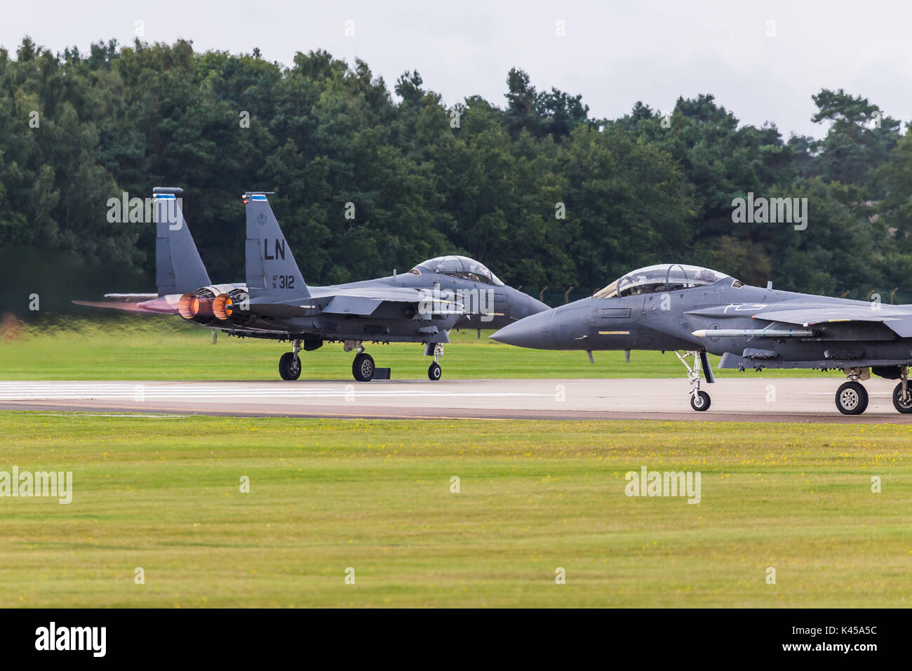 Un F-15E (de l'Aigle forgé 492 Escadron de chasse) part RAF Lakenheath dans Suffolk comme son ailier des taxis sur la piste derrière elle. Banque D'Images