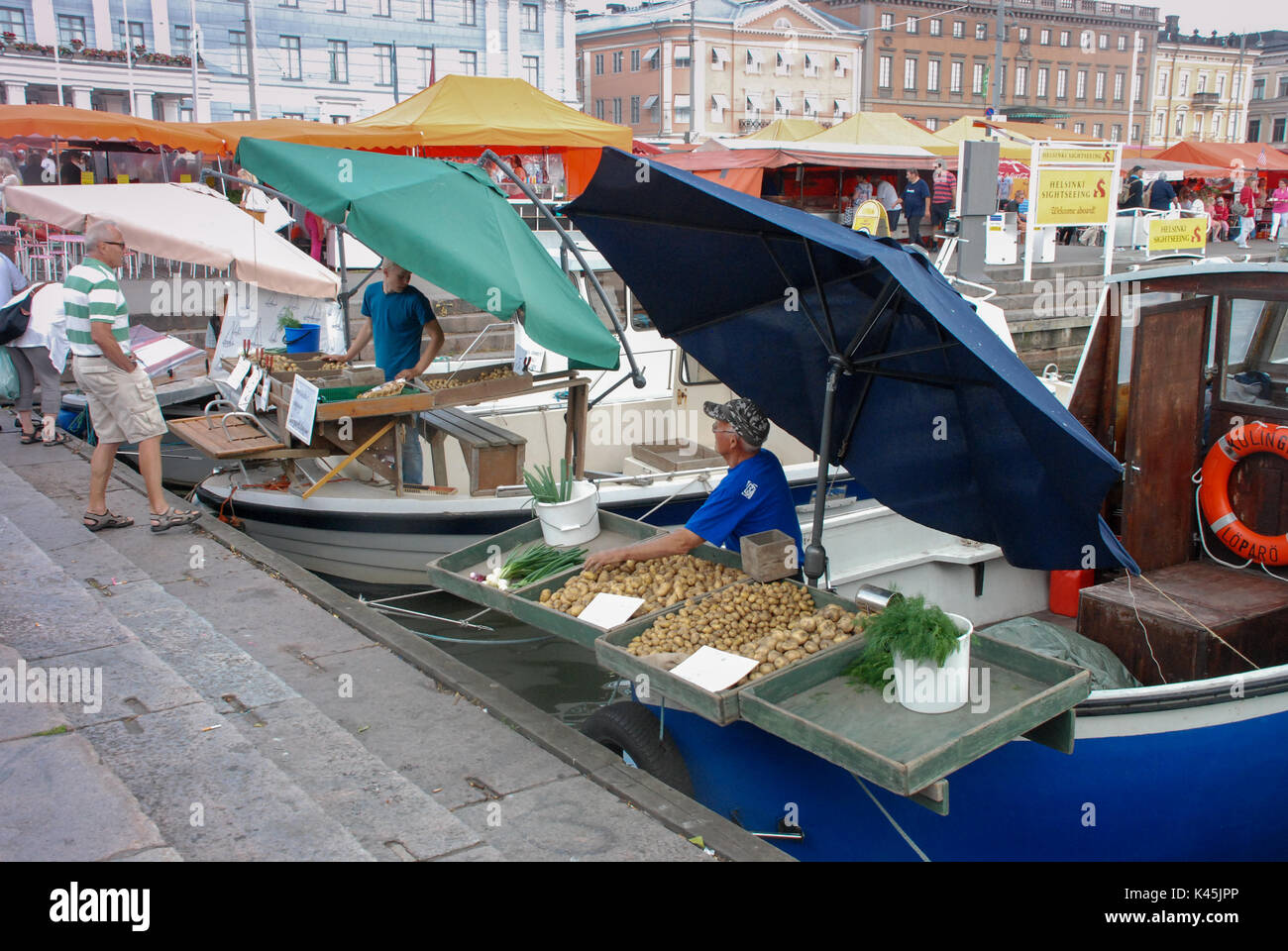 Les hommes la vente de légumes à partir de bateaux dans le port d'Helsinki, la capitale de la Finlande Banque D'Images