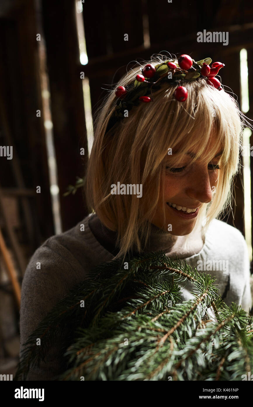 Femme blonde, coiffe, Garland avec églantier, les rameaux des arbres à feuillage persistant pour la décoration, portrait Banque D'Images