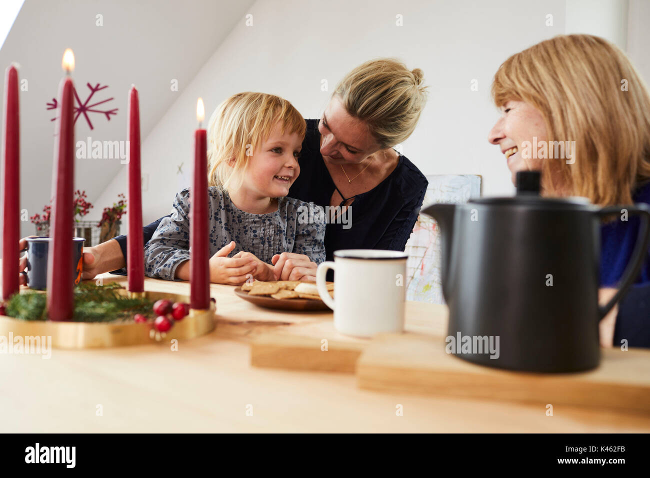 Grand-mère, mère et fille avec guirlande, assis à une table de cuisine, Banque D'Images
