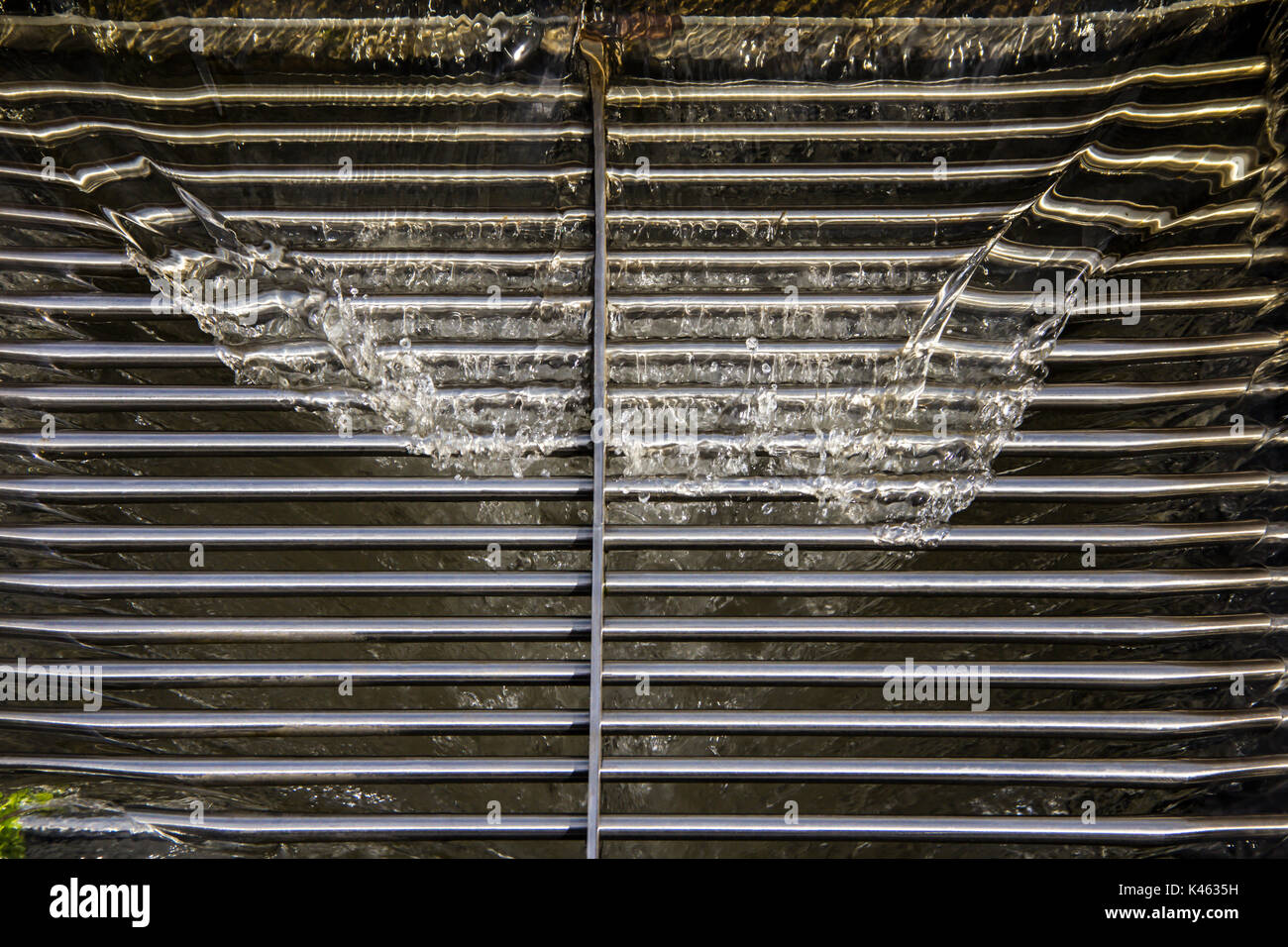 L'eau de drainage d'eau vers le bas à une grille métallique de drainage le drainage du plateau sur trottoir Banque D'Images