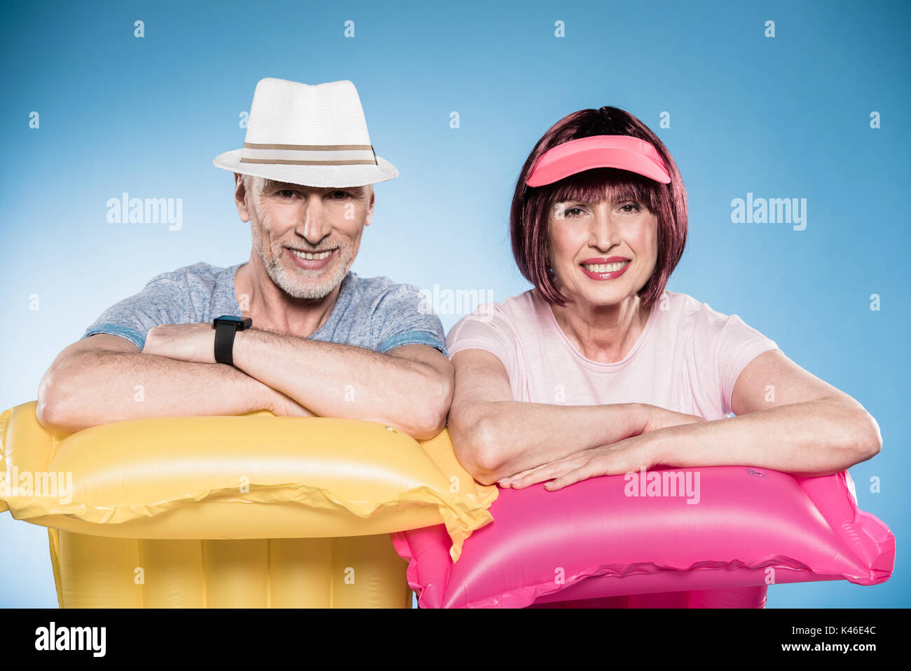 Happy senior couple looking at camera et s'appuyant sur des matelas piscine colorée Banque D'Images